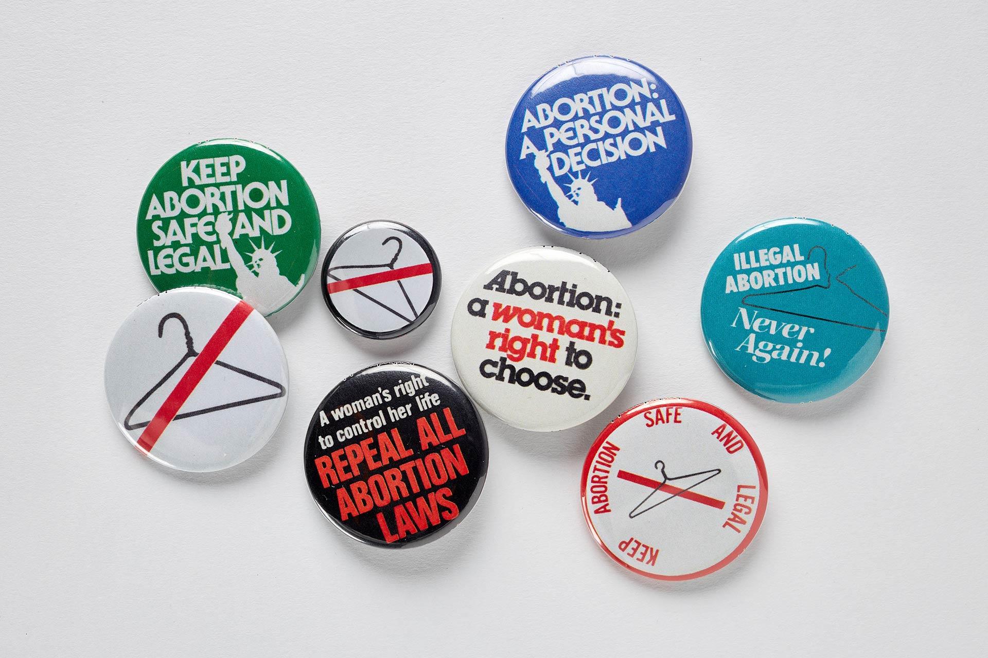 A collection of pro-choice and abortion rights buttons with slogans like “Keep abortion safe and legal,” “Abortion: a woman’s right to choose,” and images of coat hangers.